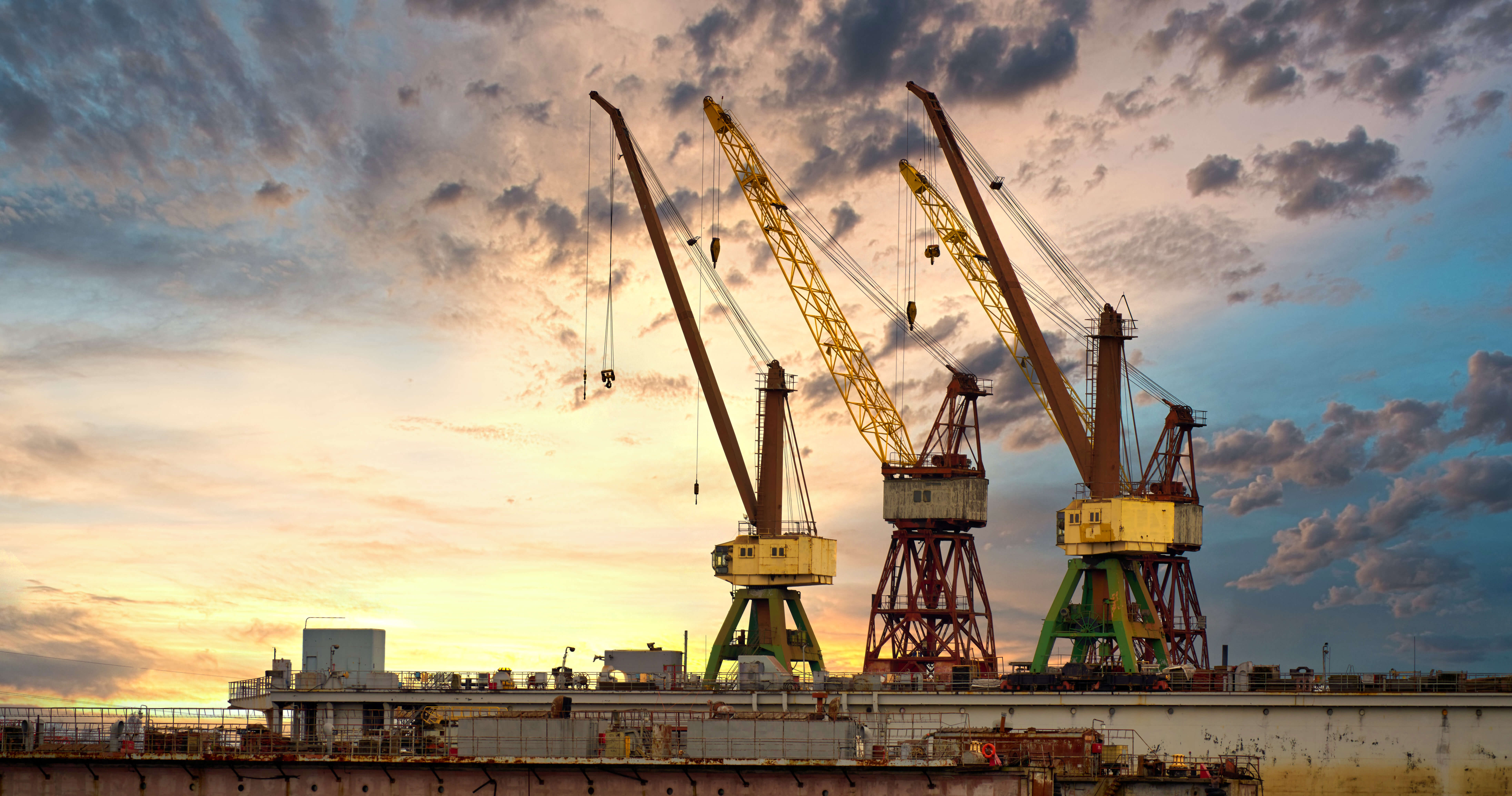 Massive,Blue,,Orange,And,Yellow,Cranes,In,Harbour
